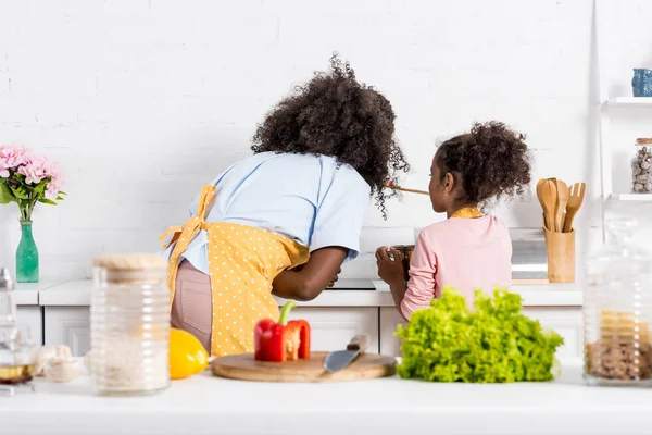 Vue arrière de la cuisine de la mère afro-américaine et l'enfant sur la cuisine — Photo de stock