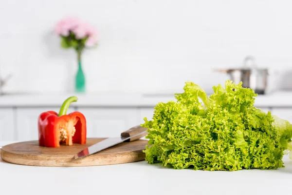 Paprika und Salat auf Holzbrett mit Messer in der Küche — Stockfoto
