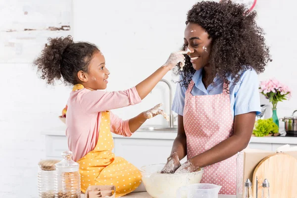 African american mother and daughter having fun while making dough on kitchen — Stock Photo