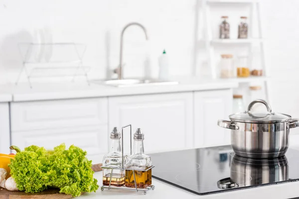 Ingredientes frescos e fogão elétrico com panela na cozinha — Fotografia de Stock