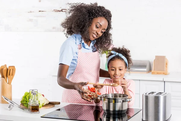 Afro-américaine maman et fille cuisine sur cuisinière électrique ensemble — Photo de stock