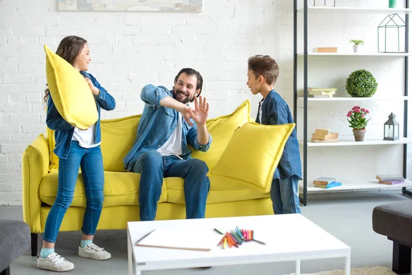 Glücklicher Vater und süße kleine Kinder, die zusammen Spaß haben und zu Hause mit Kissen spielen — Stockfoto