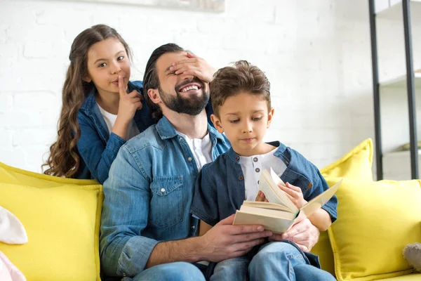 Happy father with cute little children reading book together at home — Stock Photo
