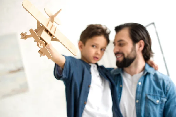 Primer plano vista de padre e hijo jugando con avión de juguete de madera - foto de stock