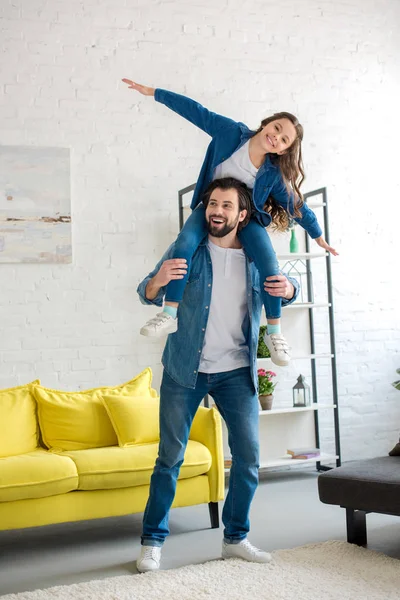 Heureux père portant adorable petite fille sur le cou et s'amuser ensemble à la maison — Photo de stock