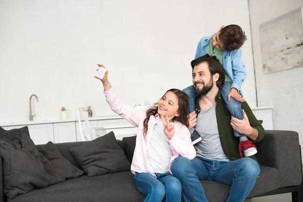 Glücklicher Vater mit zwei entzückenden Kindern, die zu Hause ein Selfie mit dem Smartphone machen — Stockfoto