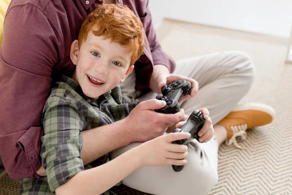 Tiro cortado de pai e filho pequeno feliz brincando com joysticks em casa — Fotografia de Stock