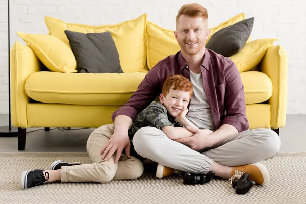 Feliz pai e filho sorrindo para a câmera enquanto passam o tempo juntos em casa — Fotografia de Stock