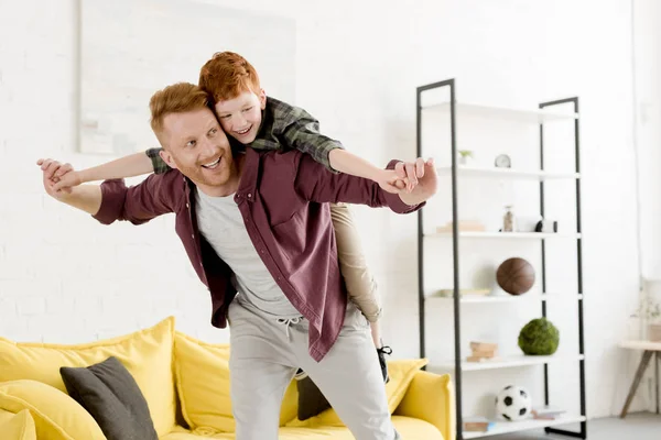 Веселый рыжий отец и сын веселятся вместе дома — стоковое фото