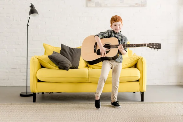 Adorable petit garçon heureux jouant de la guitare à la maison — Photo de stock