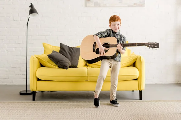 Adorable happy little boy playing guitar at home — Stock Photo