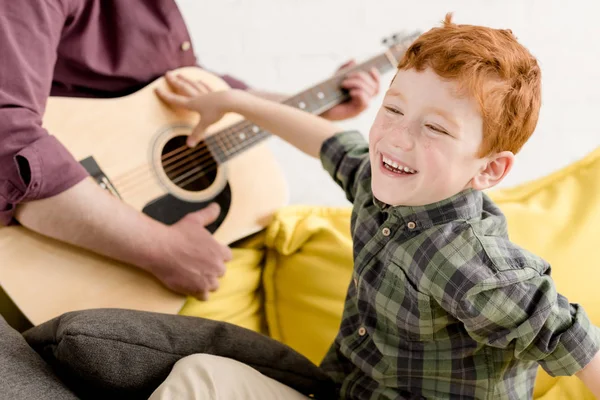 Обрізаний знімок милий маленький хлопчик сміється і батько грає на гітарі — стокове фото