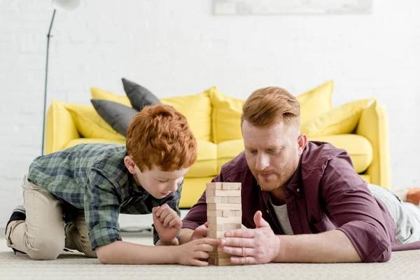 Père et fils concentrés jouant avec des blocs de bois à la maison — Photo de stock