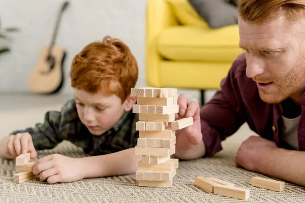 Abgeschnittene Aufnahme konzentrierter Vater und Sohn, die zu Hause Türme aus Holzklötzen bauen — Stockfoto