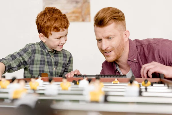 Feliz ruiva pai e filho jogando futebol de mesa juntos em casa — Fotografia de Stock