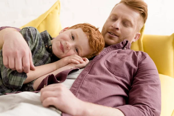 Glücklicher Vater umarmt entzückenden kleinen Sohn lächelnd in die Kamera zu Hause — Stockfoto