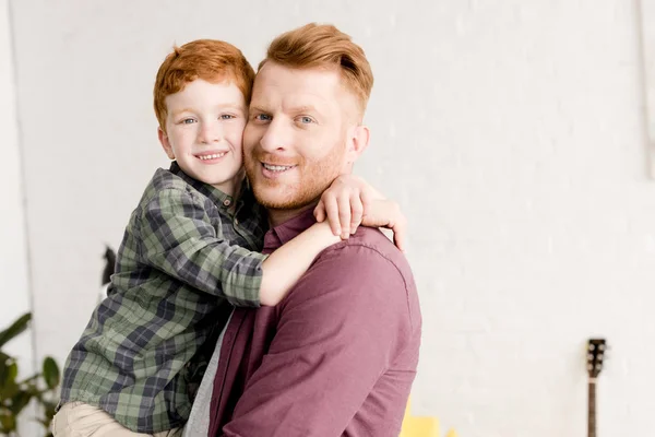 Feliz ruiva pai e filho abraçando e sorrindo para a câmera — Fotografia de Stock