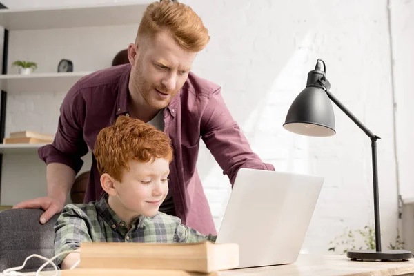 Redhead father and son using laptop together at home — Stock Photo