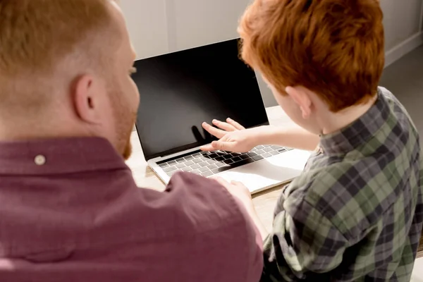 Foyer sélectif du père et du fils à l'aide d'un ordinateur portable avec écran blanc — Photo de stock