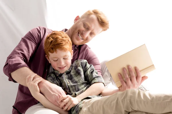 Happy father and son having fun together while reading book at home — Stock Photo