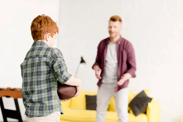 Redhead father and son playing with rugby ball at home — Stock Photo