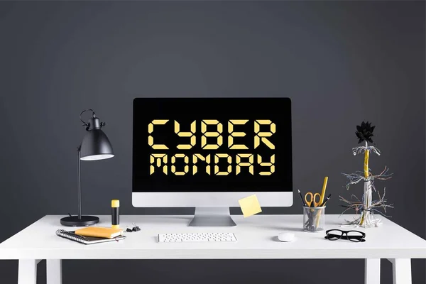 Desktop computer with inscription cyber monday on screen, lamp and office supplies on table on grey — Stock Photo