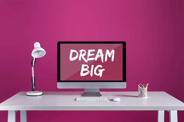 Desktop computer with dream big inscription on screen, keyboard, computer mouse and office supplies on table — Stock Photo