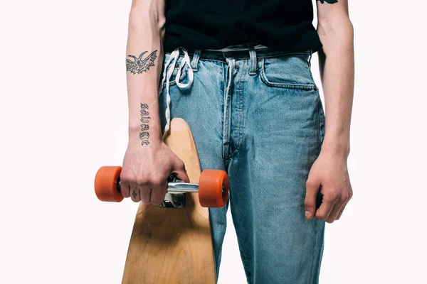 Обрезанный вид человека в джинсах с длинной доской, изолированной на белом — стоковое фото