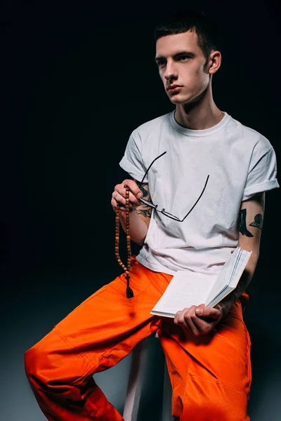 Thoughtful male prisoner holding bible on dark background — Stock Photo