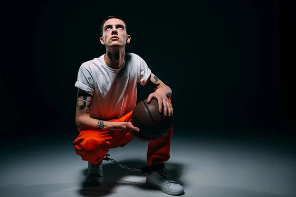 Prisoner with basketball ball looking up on dark background — Stock Photo