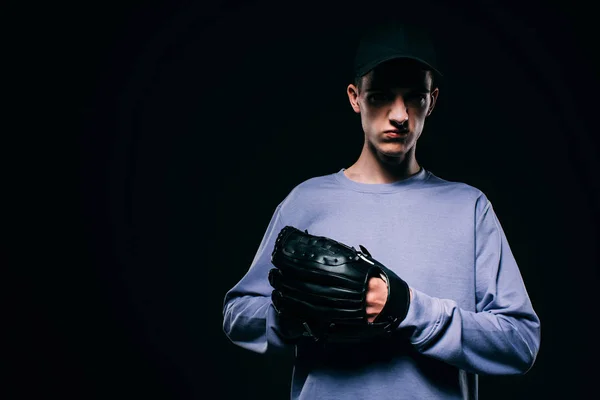Hombre con gorra de béisbol usando guante de béisbol aislado en negro - foto de stock