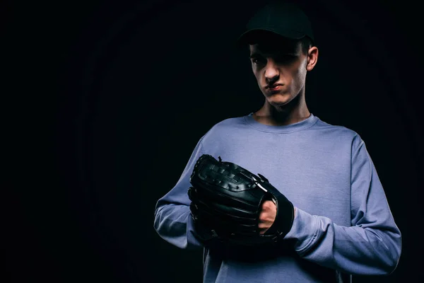 Bonito jovem com luva de beisebol isolado em preto — Fotografia de Stock