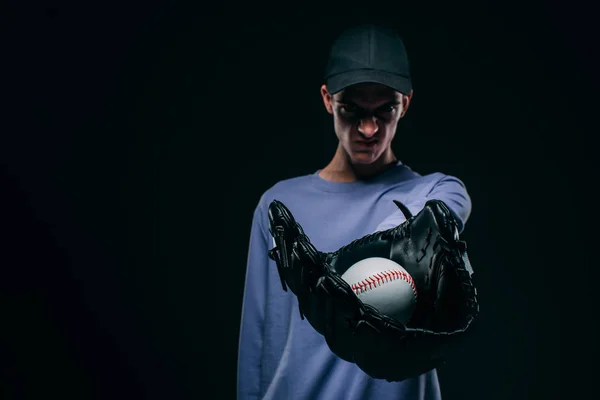 Hombre enojado usando guante de béisbol mostrando pelota de béisbol aislado en negro - foto de stock
