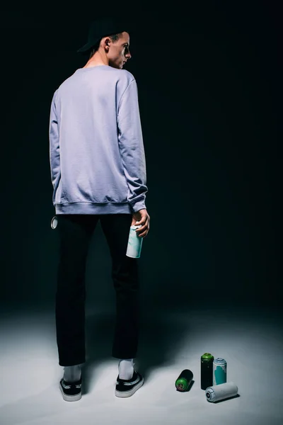 Schöner Mann steht mit Sprühfarbe auf dunklem Hintergrund — Stockfoto