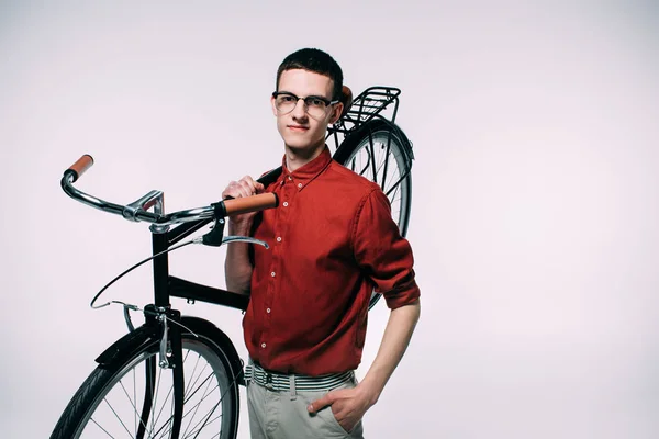 Усміхнений молодий чоловік тримає свій велосипед на плечі ізольовано на білому — стокове фото