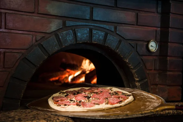 Close up view of cooking process of raw pizza on wooden stove in brick oven — Stock Photo