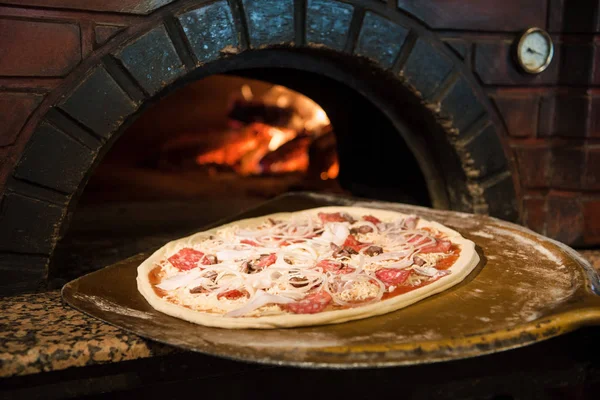 Vue rapprochée du processus de cuisson de la pizza crue sur poêle à bois au four à briques — Photo de stock
