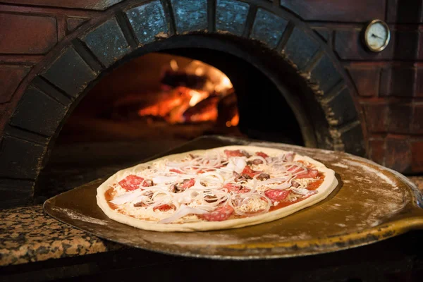 Close up view of cooking process of raw pizza on wooden stove in brick oven — Stock Photo