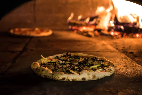 Vista de cerca de la pizza italiana hornear en horno de ladrillo en el restaurante - foto de stock