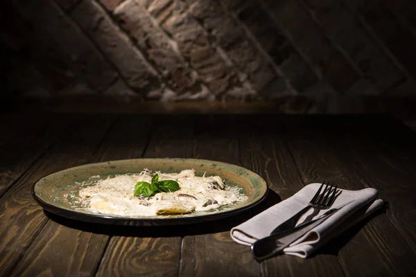 Vue rapprochée du plat italien avec couverts sur serviette sur surface en bois — Photo de stock