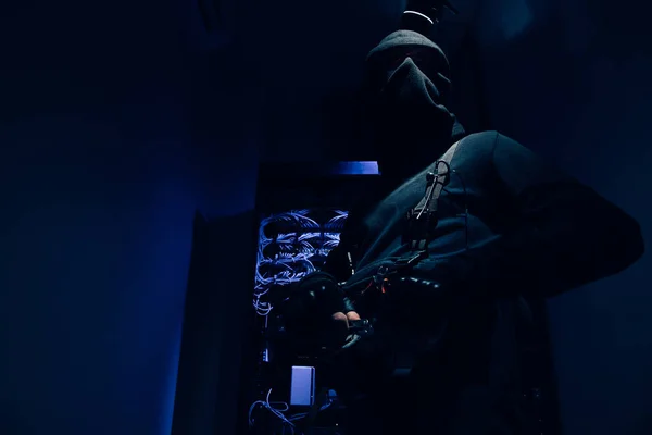 Low angle view of hacker in black clothing with various cables on background — Stock Photo