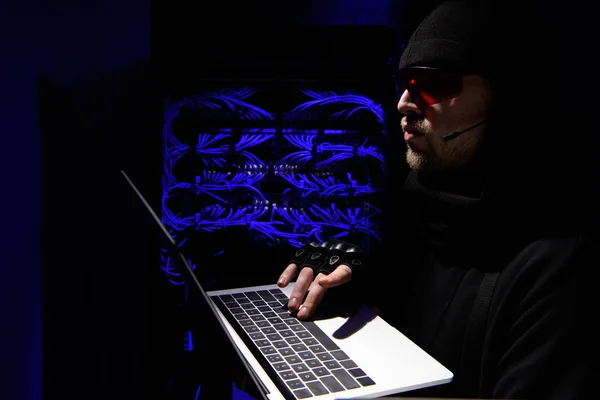 Side view of hacker in eyeglasses using laptop with cables on background — Stock Photo