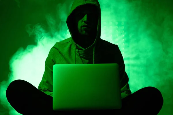 Toned picture of hacker in hoodie with laptop — Stock Photo