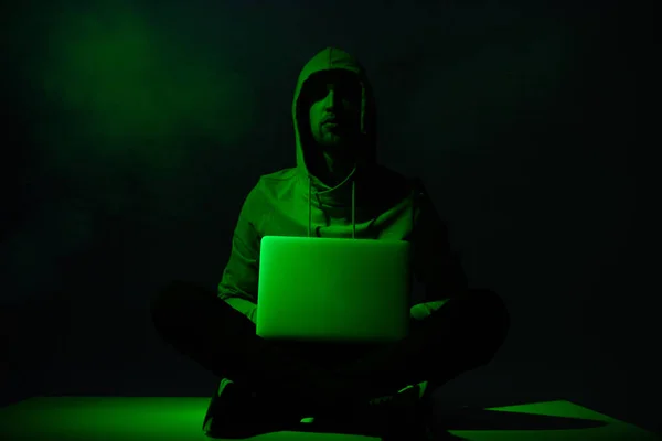 Toned picture of hacker in hoodie with laptop — Stock Photo