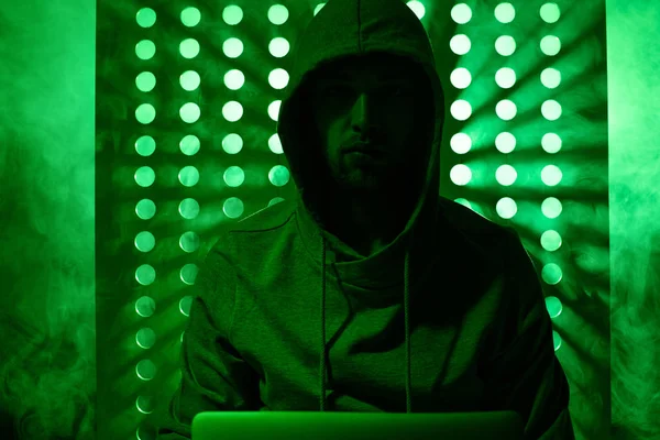 Getöntes Bild eines männlichen Hackers im Kapuzenpulli mit Laptop — Stockfoto