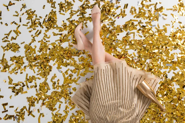 Cropped image of woman lying on golden confetti — Stock Photo