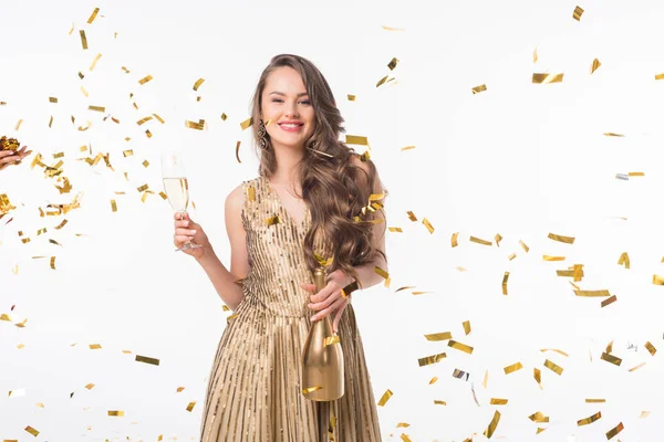 Happy woman standing with champagne under falling golden confetti isolated on white — Stock Photo