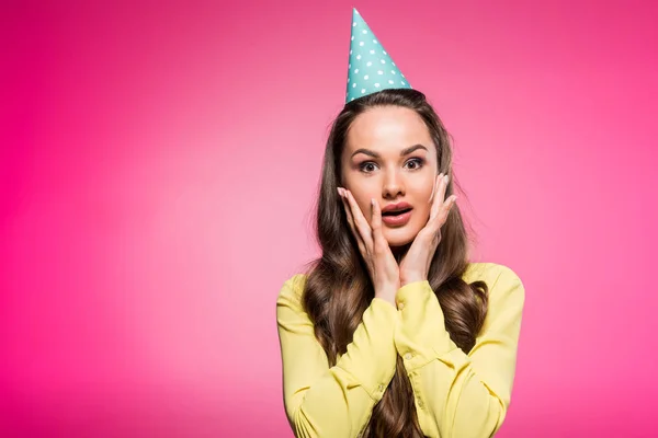 Mujer atractiva sorprendida con sombrero de fiesta aislado en rosa - foto de stock