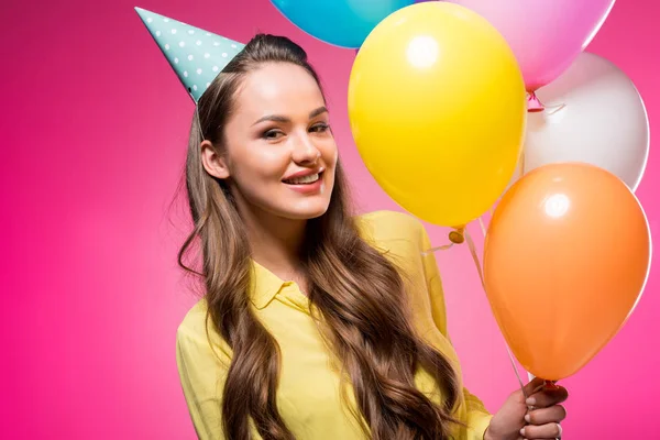 Retrato de mujer con sombrero de fiesta y globos aislados en rosa - foto de stock