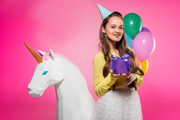 Attraktive Frau mit Partyhut und Geschenkbox isoliert auf rosa — Stockfoto